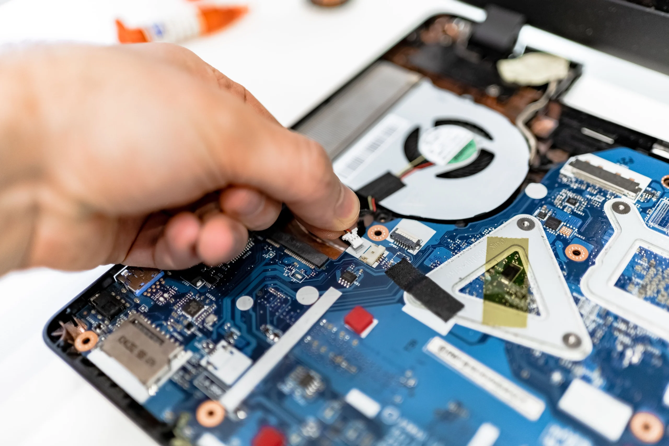 Technicien qui remplace un composant dans un ordinateur portable ouvert