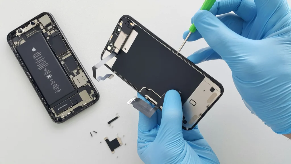 Technicien en gants bleus qui ouvre un iPhone pour remplacer l’écran ou la batterie